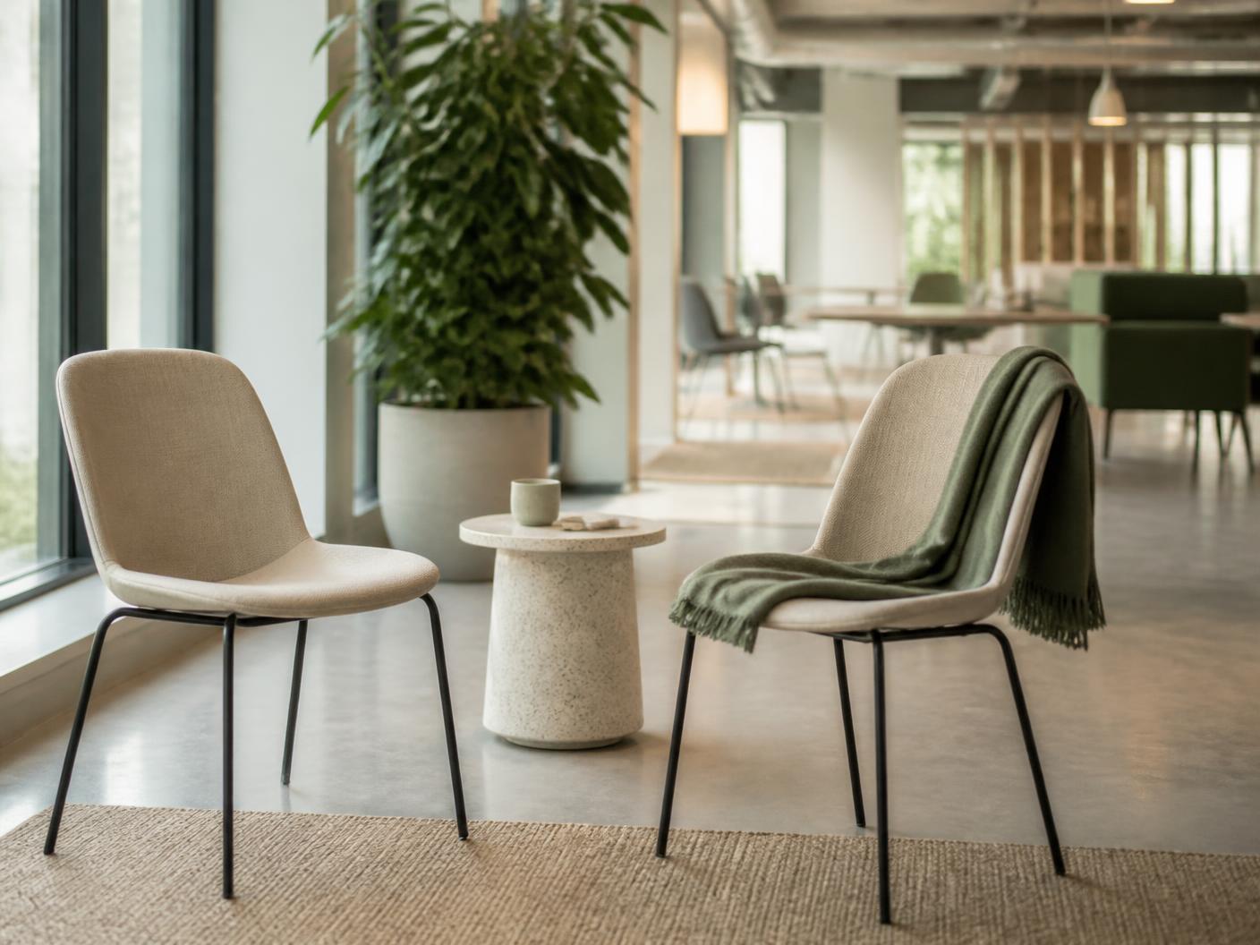 Two soft chairs and a small table set up for a wellness session in a bright workplace